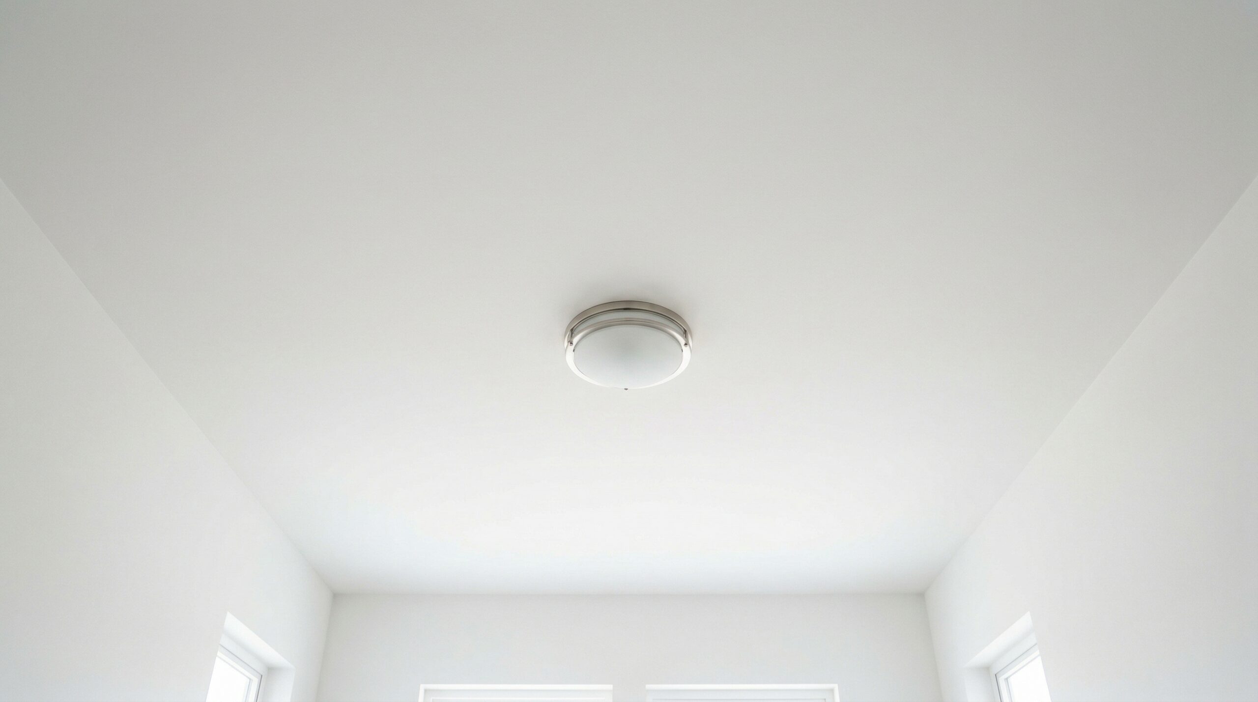 明るい部屋から見上げた白い天井とシーリングライト。異常のない一般的な住宅の室内