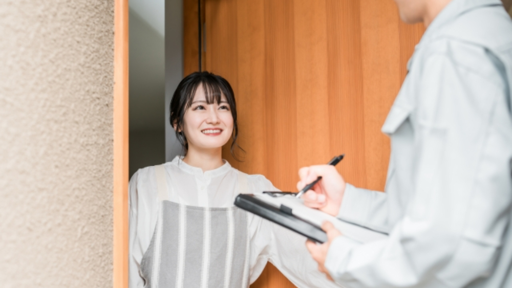 訪問営業に来た男性の話を聞く笑顔の主婦