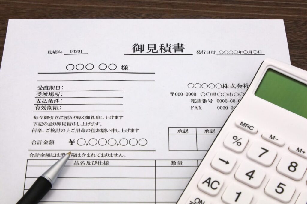 机に書類（見積書・電卓・ペン）が置かれた俯瞰カット
