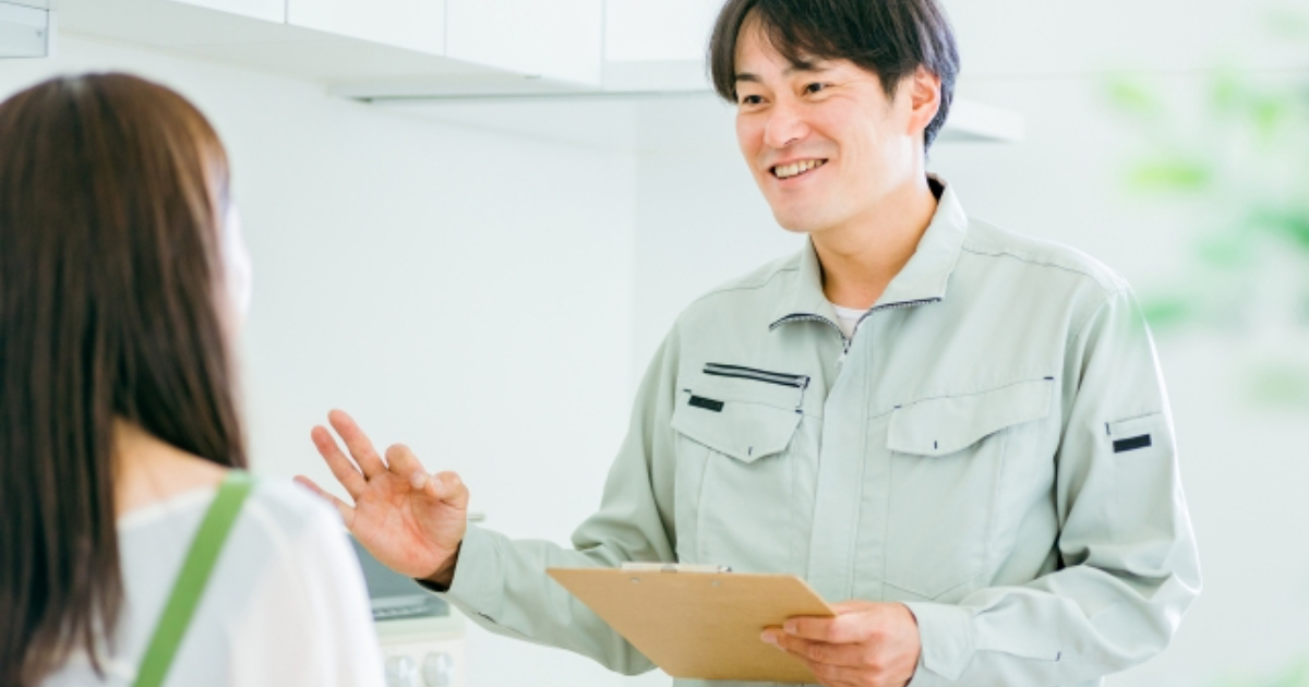 キッチンと作業着姿の男性（水道・笑顔）